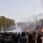 Manifestants et forces de l'ordre face à des barricades en feu devant l'Arc de Triomphe à Montpellier.