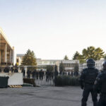 Des policiers en tenue anti-émeute font face à un groupe d'étudiants derrière une grille à l'université de Montpellier.