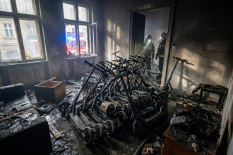 Pompiers inspectant un appartement calciné rempli de dizaines de trottinettes électriques brûlées.